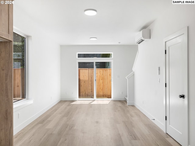 empty room with a wall unit AC and light wood-type flooring