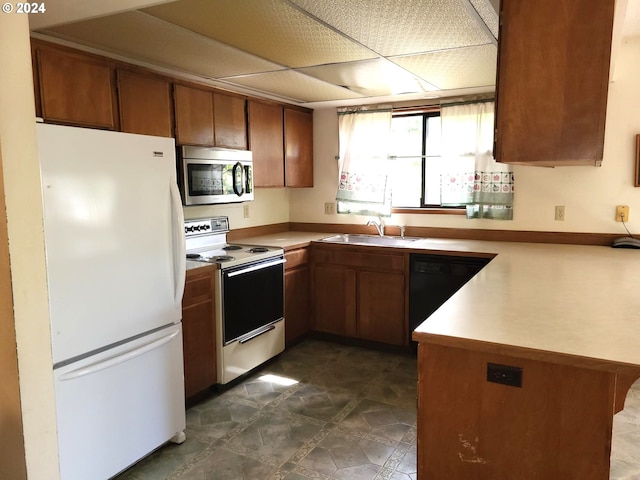 kitchen featuring sink, kitchen peninsula, and white appliances