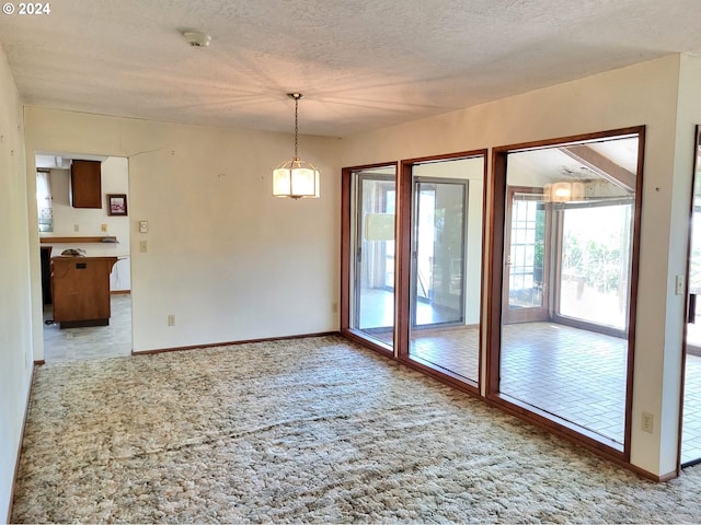 empty room with a textured ceiling and light colored carpet