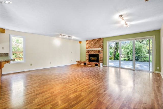 unfurnished living room with hardwood / wood-style floors, a fireplace, and track lighting