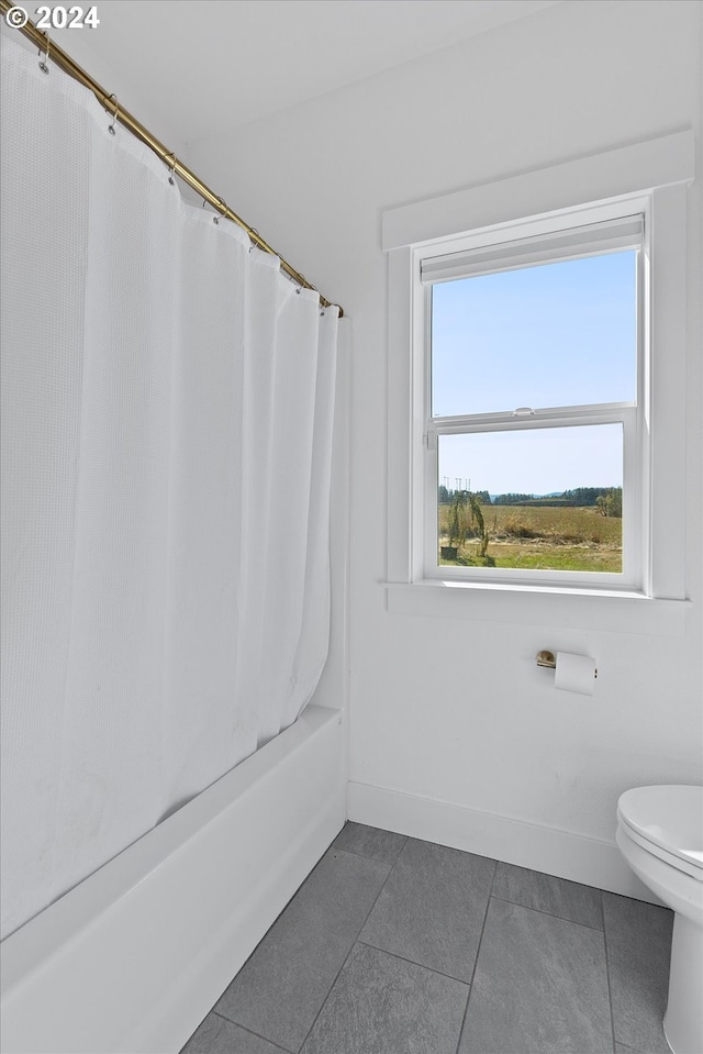 bathroom with tile patterned floors, shower / bath combo with shower curtain, and toilet