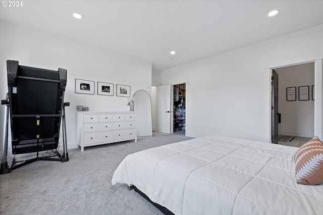 bedroom featuring connected bathroom, a walk in closet, a closet, and light colored carpet