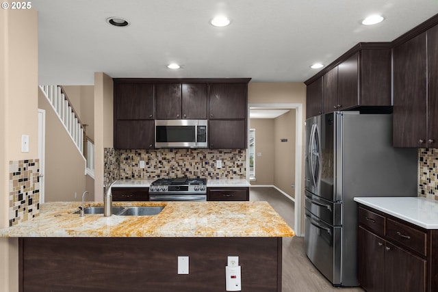 kitchen with light hardwood / wood-style flooring, sink, stainless steel appliances, tasteful backsplash, and dark brown cabinetry