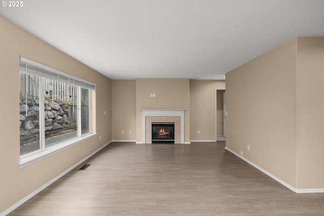 unfurnished living room featuring a tile fireplace and light wood-type flooring