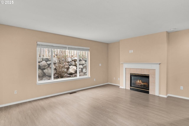 unfurnished living room with hardwood / wood-style floors and a tile fireplace