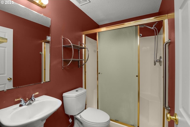 bathroom with sink, an enclosed shower, a textured ceiling, and toilet