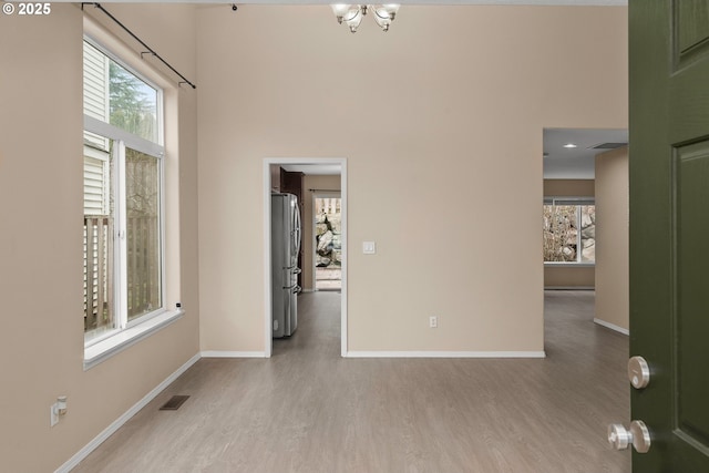 spare room featuring a high ceiling, light hardwood / wood-style flooring, and a chandelier