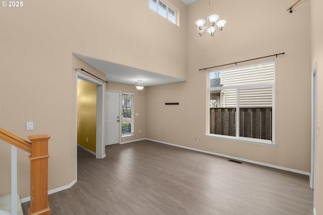 unfurnished room featuring a notable chandelier, a high ceiling, and hardwood / wood-style flooring