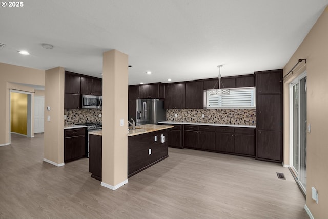 kitchen featuring light hardwood / wood-style floors, stainless steel appliances, decorative backsplash, and dark brown cabinetry