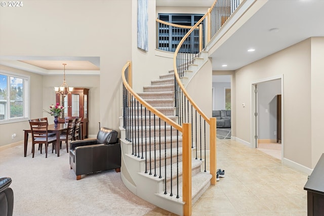 staircase with a tray ceiling and a chandelier