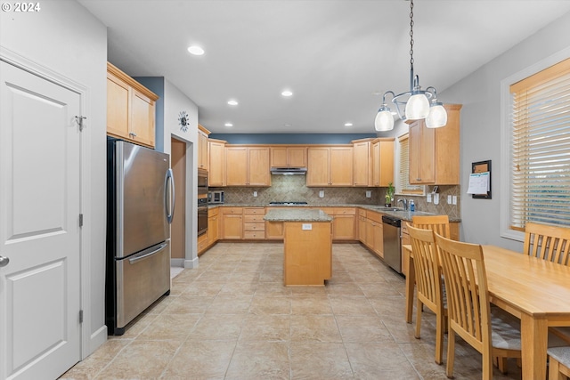 kitchen with decorative backsplash, appliances with stainless steel finishes, light brown cabinetry, sink, and a center island