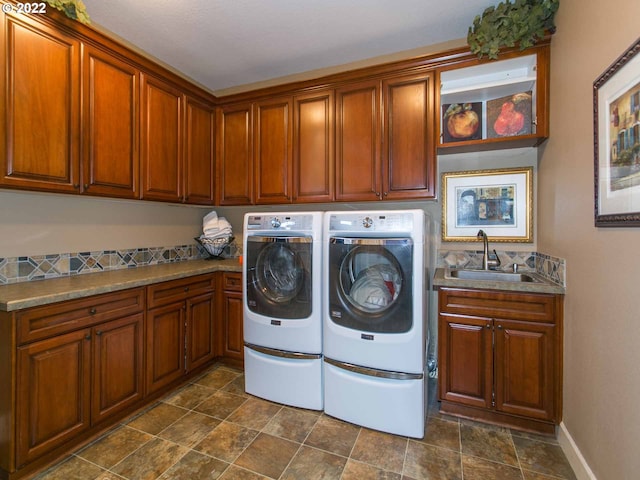 laundry room featuring sink, washing machine and dryer, cabinets, and dark tile patterned floors