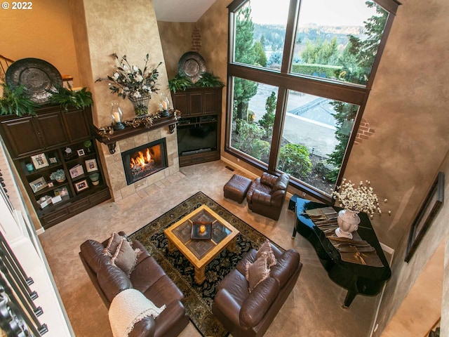 carpeted living room with a wealth of natural light, a towering ceiling, and a fireplace