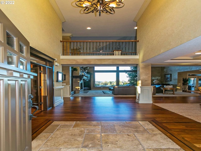 entryway with a high ceiling, wood-type flooring, ornamental molding, and an inviting chandelier