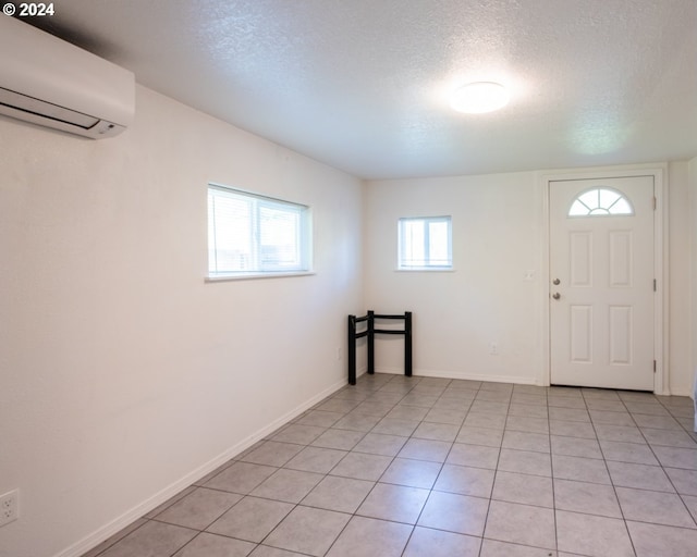 tiled foyer with a wall mounted air conditioner and a textured ceiling