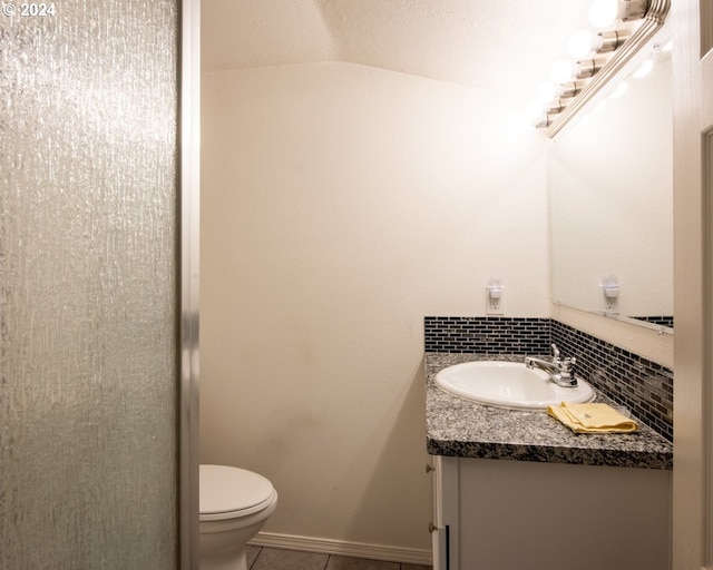 bathroom featuring decorative backsplash, vanity, vaulted ceiling, tile patterned flooring, and toilet