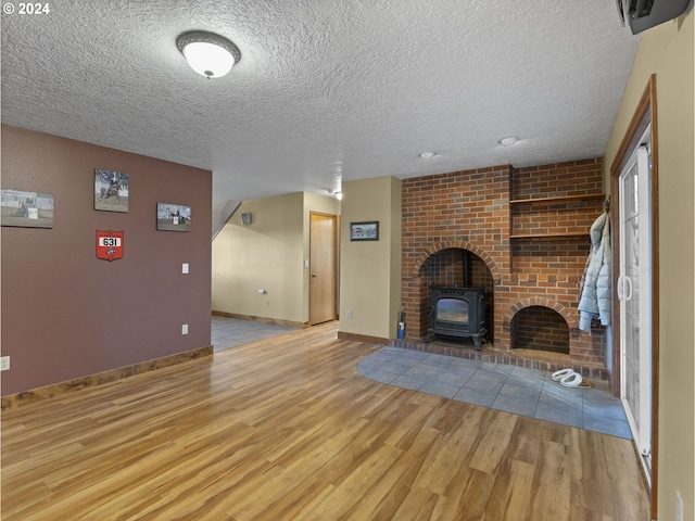 unfurnished living room with a wood stove, light hardwood / wood-style floors, and a textured ceiling