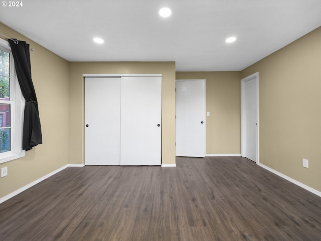 unfurnished bedroom with dark wood-type flooring and a closet