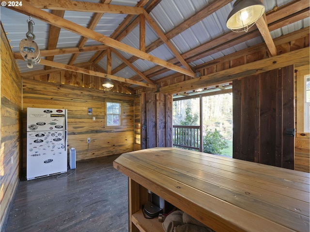 unfurnished dining area featuring dark hardwood / wood-style flooring, vaulted ceiling with beams, and wooden walls