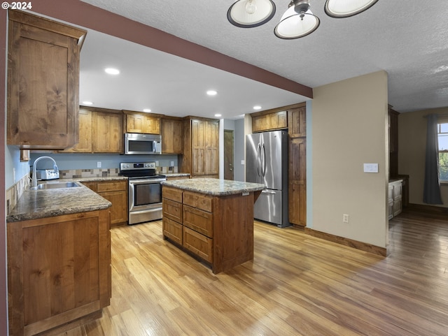 kitchen with a center island, sink, light hardwood / wood-style flooring, a textured ceiling, and stainless steel appliances