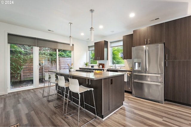 kitchen featuring a breakfast bar area, a center island, light hardwood / wood-style floors, appliances with stainless steel finishes, and pendant lighting