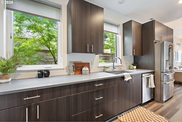 kitchen with stainless steel appliances, light hardwood / wood-style floors, dark brown cabinets, and sink