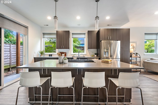 kitchen featuring stainless steel fridge with ice dispenser, a center island, light hardwood / wood-style floors, and a breakfast bar