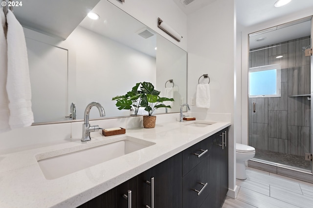 bathroom with tile patterned floors, an enclosed shower, toilet, and double sink vanity