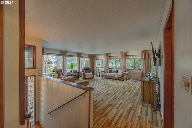 living room with light hardwood / wood-style floors, a textured ceiling, and wooden walls