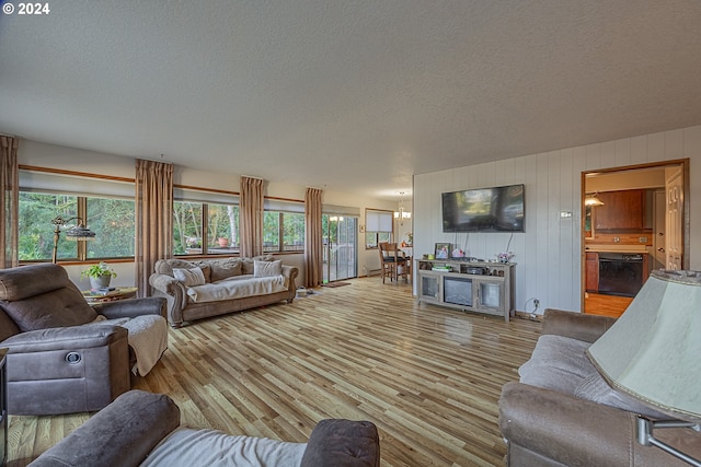 living room with a textured ceiling, an inviting chandelier, and light hardwood / wood-style flooring