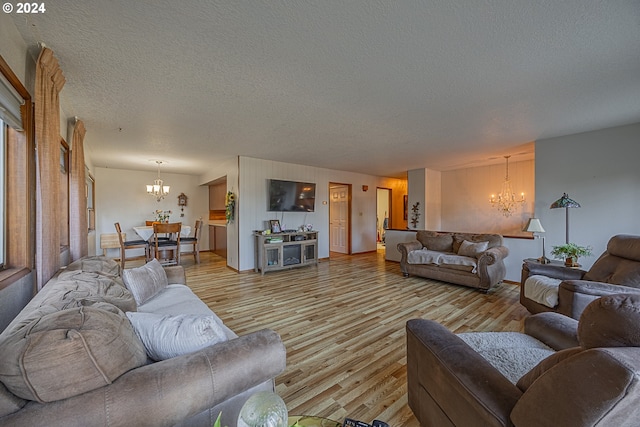 living room with light hardwood / wood-style floors, a textured ceiling, and an inviting chandelier