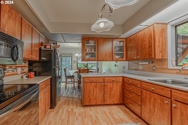 kitchen featuring black appliances, tasteful backsplash, sink, and light hardwood / wood-style flooring