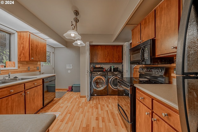 kitchen featuring light wood-type flooring, washing machine and dryer, a wealth of natural light, and black appliances