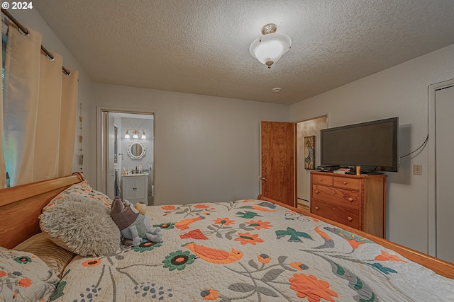 bedroom featuring a textured ceiling, ensuite bath, and sink