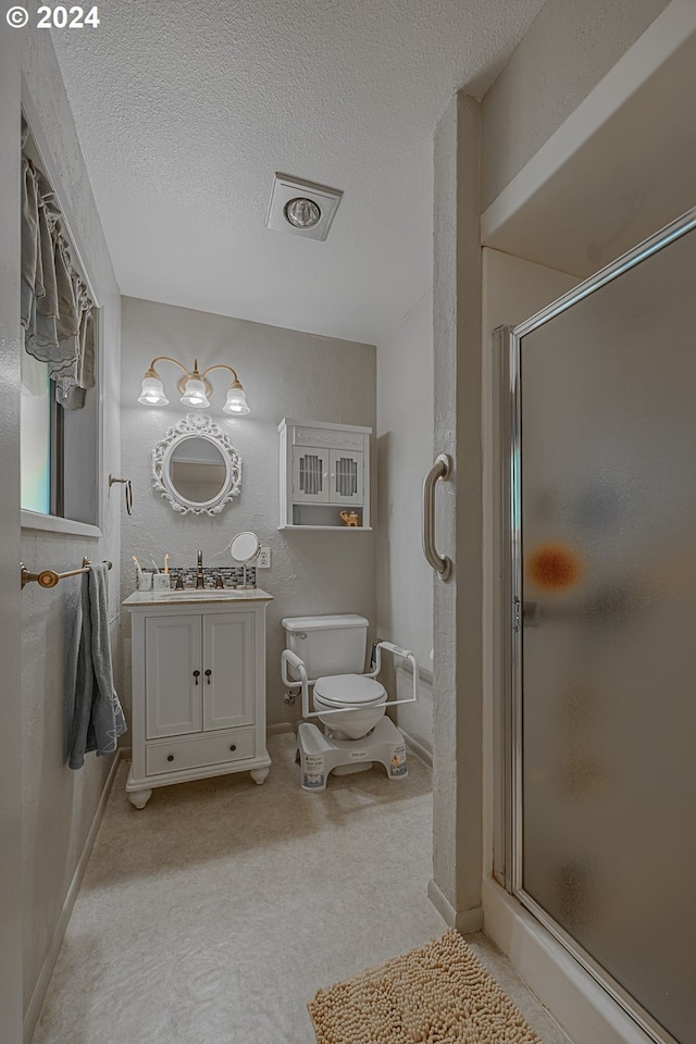 bathroom featuring vanity, a textured ceiling, toilet, and a shower with shower door