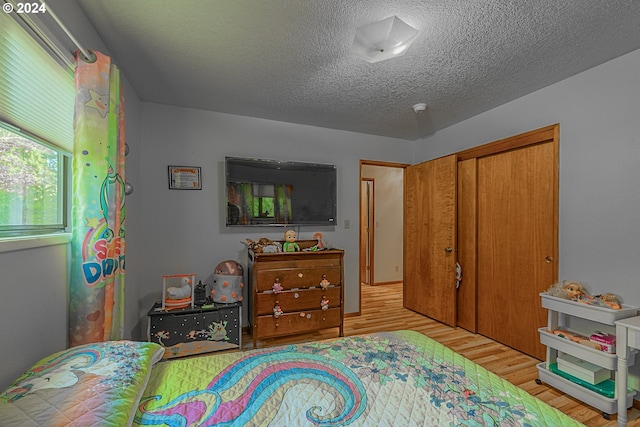 bedroom featuring a closet, light hardwood / wood-style floors, and a textured ceiling