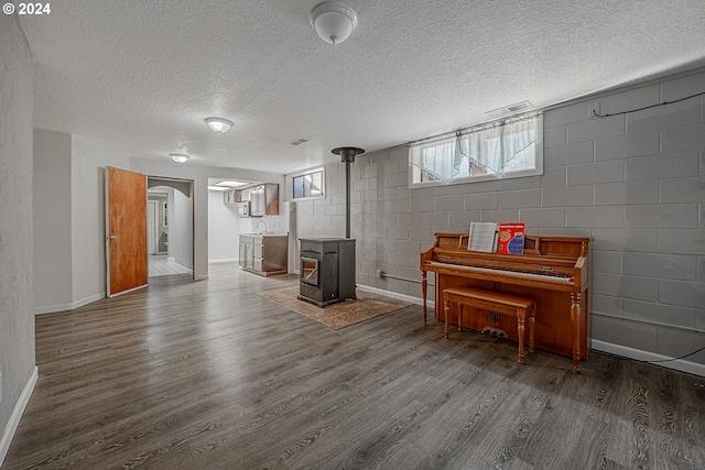 interior space featuring a textured ceiling, dark hardwood / wood-style flooring, a wood stove, and sink