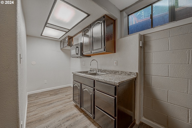 kitchen with dark brown cabinets, light hardwood / wood-style floors, and sink