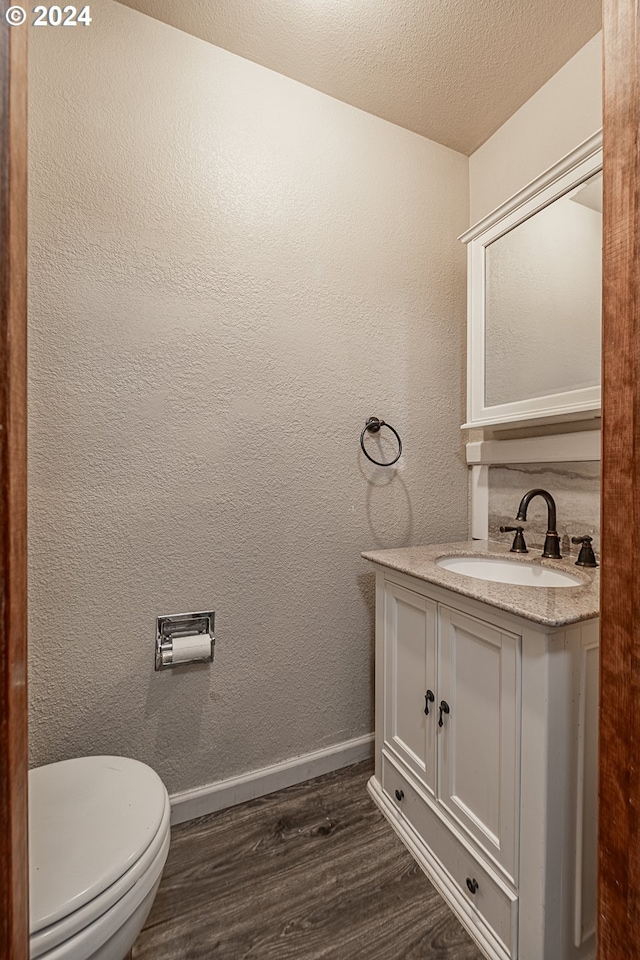 bathroom featuring hardwood / wood-style floors, vanity, toilet, and a textured ceiling