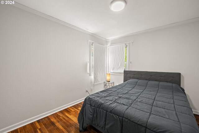 bedroom with ornamental molding and dark hardwood / wood-style flooring