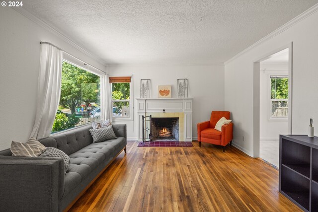 living room with ornamental molding, a textured ceiling, hardwood / wood-style flooring, and a tile fireplace