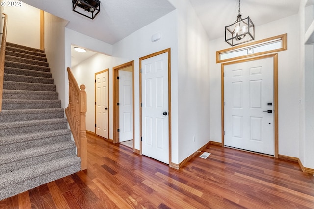 entryway featuring dark wood-type flooring and an inviting chandelier