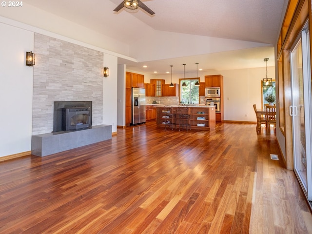 2201 NW Carty Rd, Ridgefield, WA 98642 - living area with vaulted ceiling, a ceiling fan, dark wood-type flooring, a tiled fireplace, and baseboards