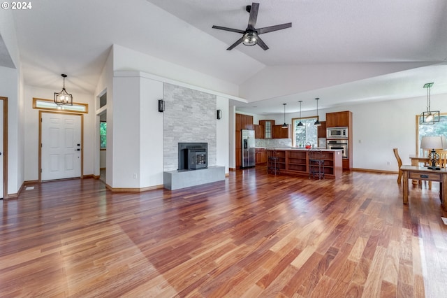 2201 NW Carty Rd, Ridgefield, WA 98642 - living room featuring a chandelier, ceiling fan, wood finished floors, vaulted ceiling, and a stone fireplace