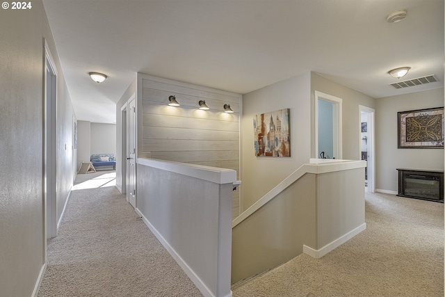 hallway with carpet, an upstairs landing, visible vents, and baseboards