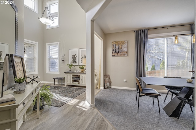 interior space featuring a high ceiling, baseboards, and light wood-type flooring