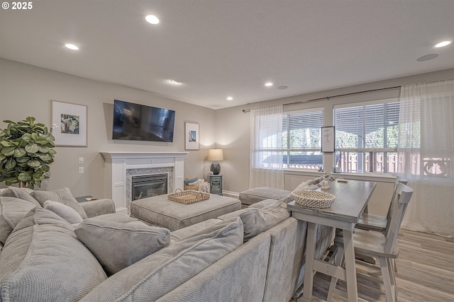 living area featuring recessed lighting, light wood-style floors, and a premium fireplace