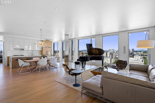 living room featuring a notable chandelier, a wall of windows, and light hardwood / wood-style flooring