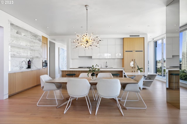 dining area featuring a chandelier, light hardwood / wood-style floors, and sink