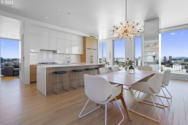 dining area featuring a chandelier, light hardwood / wood-style floors, and a wall of windows